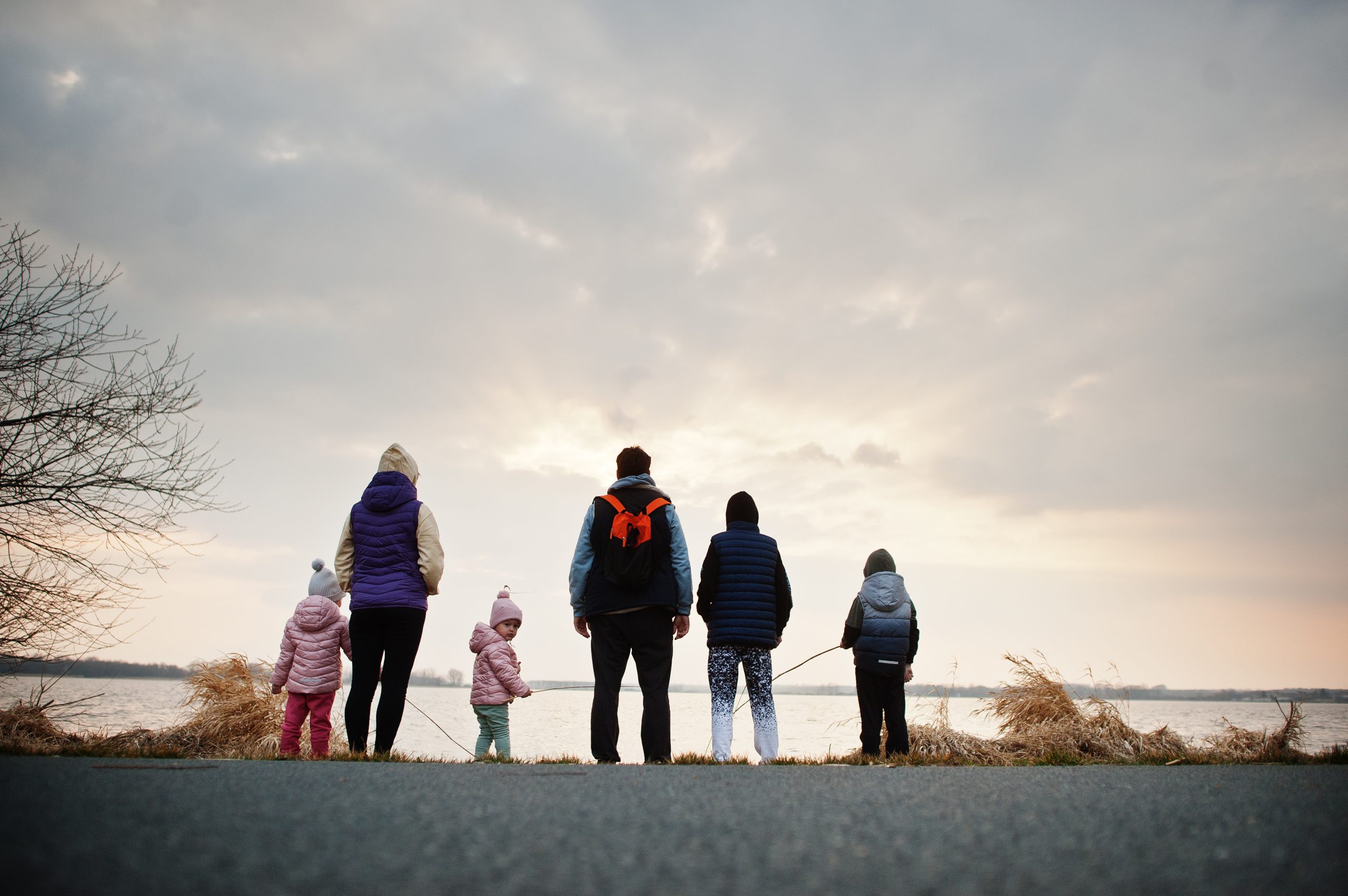 Back of family with four kids on the shore of the lake.